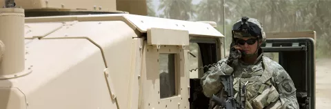 Soldier communicates with a radio mounted in an armored HMMWV