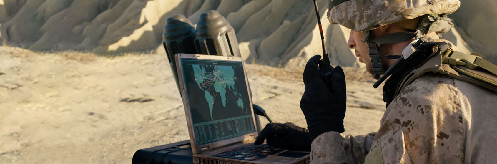 Soldier is Using Laptop Computer and Radio for Communication During Military Operation in the Desert