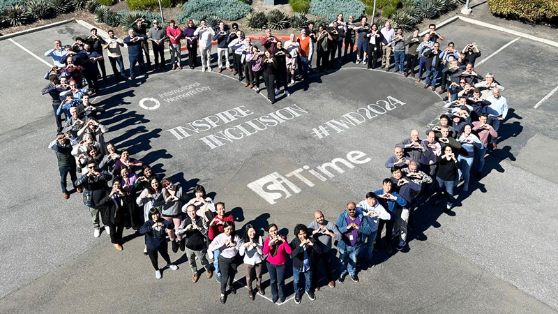 Large group of people gathered in the shape of a heart making heart shape with their hands. International Women's Day