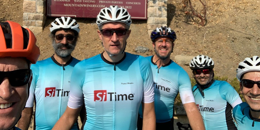 SiTime employees wearing a summer cycling kit comprising a helmet, short-sleeved jersey, mitts, bib shorts.
