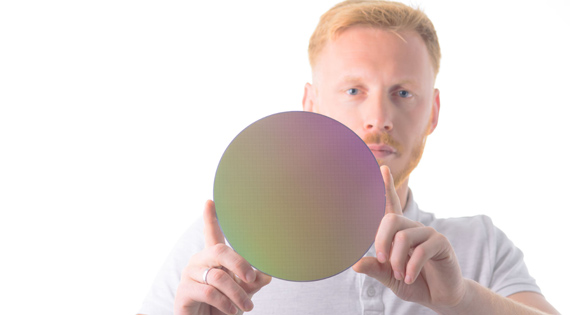 Page: Timing Transformed. Image: A man holding a silicon wafer in his hands