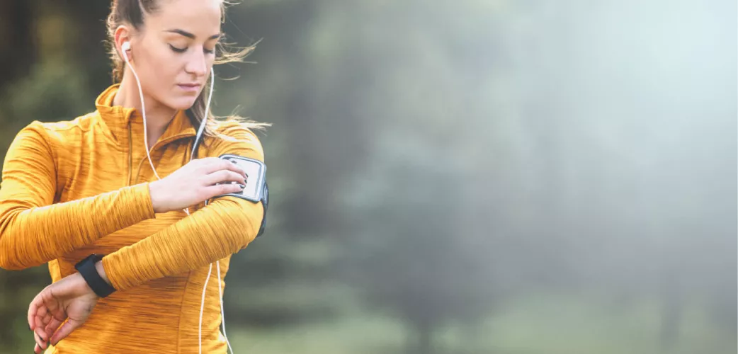 Image: A running lady listen music wearing her smartphone on a shoulder