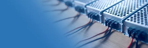 Close up of the metal mesh cases of power supply and wires are on a wooden table